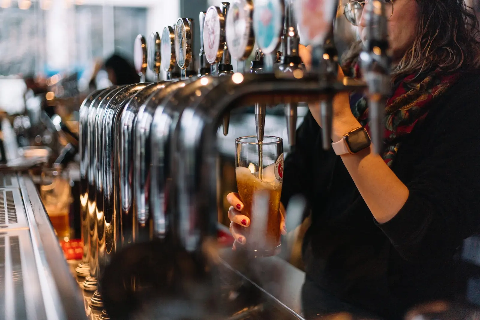 Una mujer sirve cerveza en el grifo de un bar